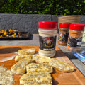 Lemon and herb seasoning displayed on a wooden cutting board with seasoned halloumi slices, set against a background of a grey stone