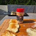 Slices of halloumi dusted with Forge & Fyre Mediterranean rub on a wooden board, with the jar of seasoning behind